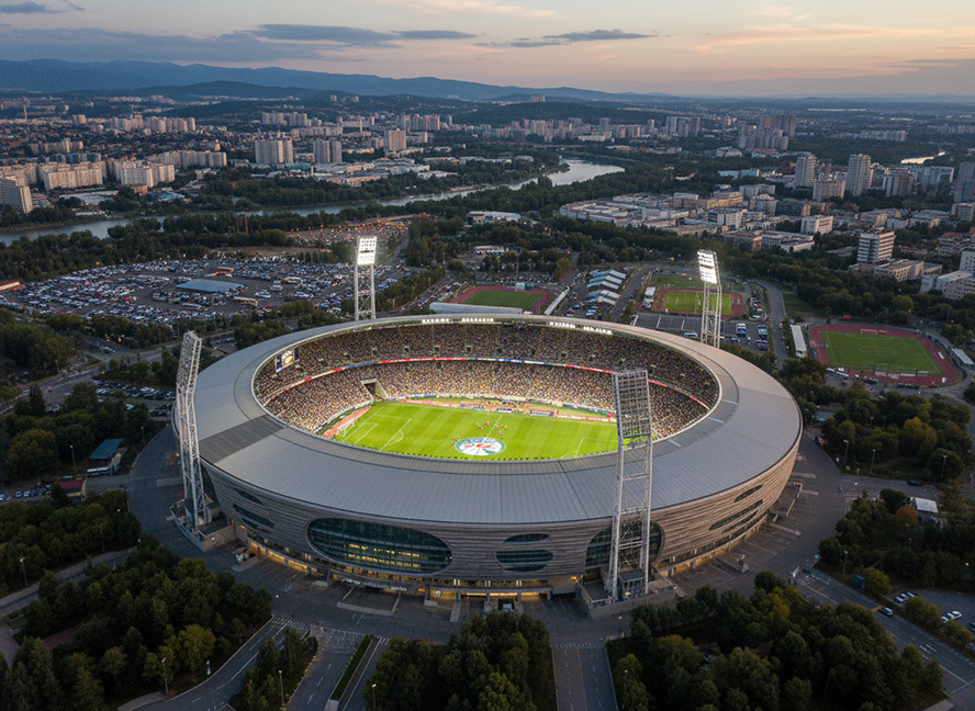 Modernes Fußballstadion bei Sonnenuntergang aus der Luftaufnahme mit Flutlicht.